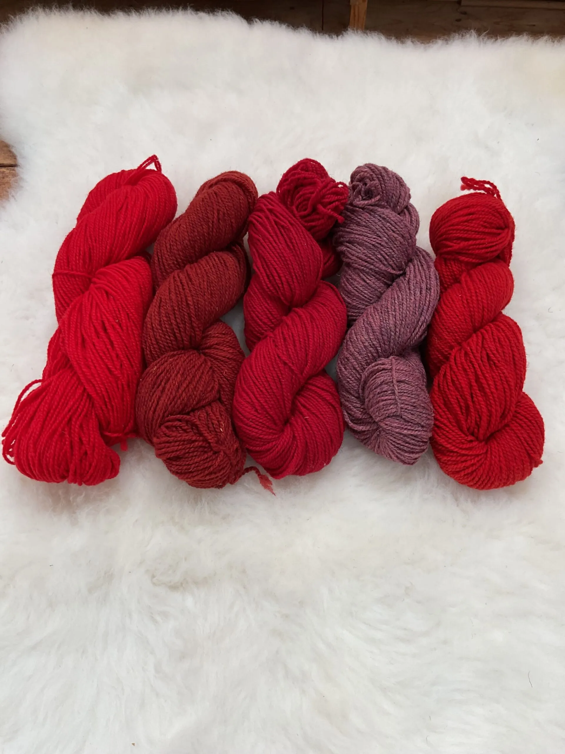 Red Philosopher’s Wool skeins in scarlet, monarch, rock, and Macintosh shades