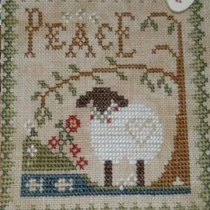 A cross-stitched sheep picture with Peace lettering