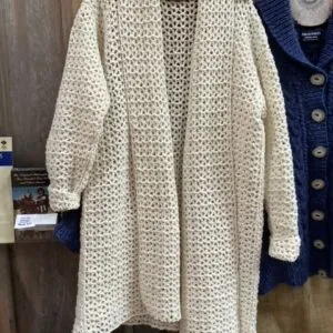 A light wool greatcoat hanging beside a cardigan